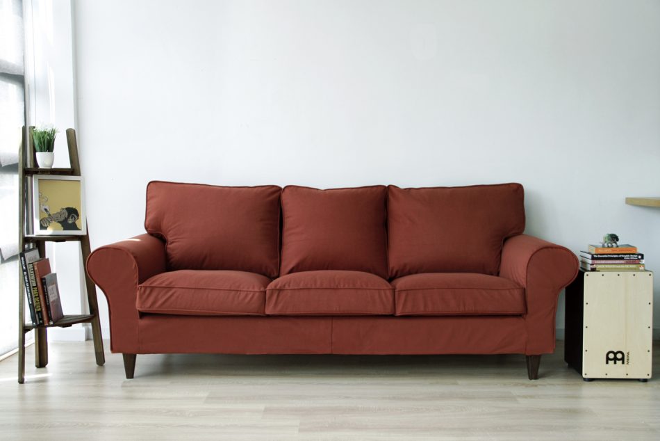 Rust-red woollen snug fit tailored sofa covers made by Comfort Works, on an IKEA Ektorp 3 seater sofa, with replacement custom stained Walker wooden sofa legs.