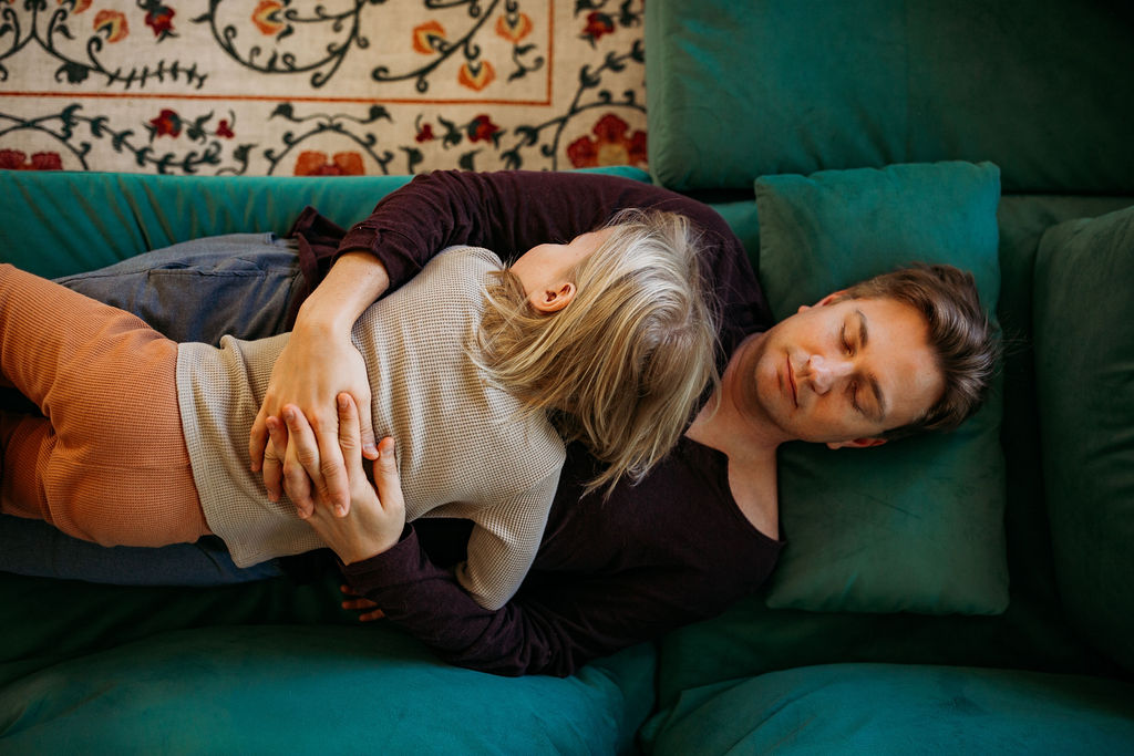 parent and child sleeping on green velvet sofa
