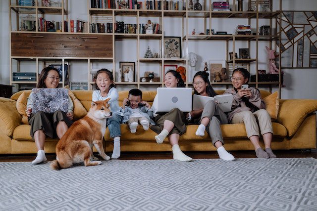 Familie mit Kindern und Hund auf gelber Couch