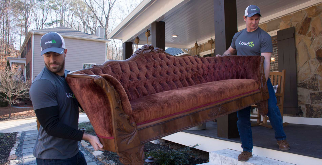 Männer in Uniformen transportieren eine Couch aus dem Haus