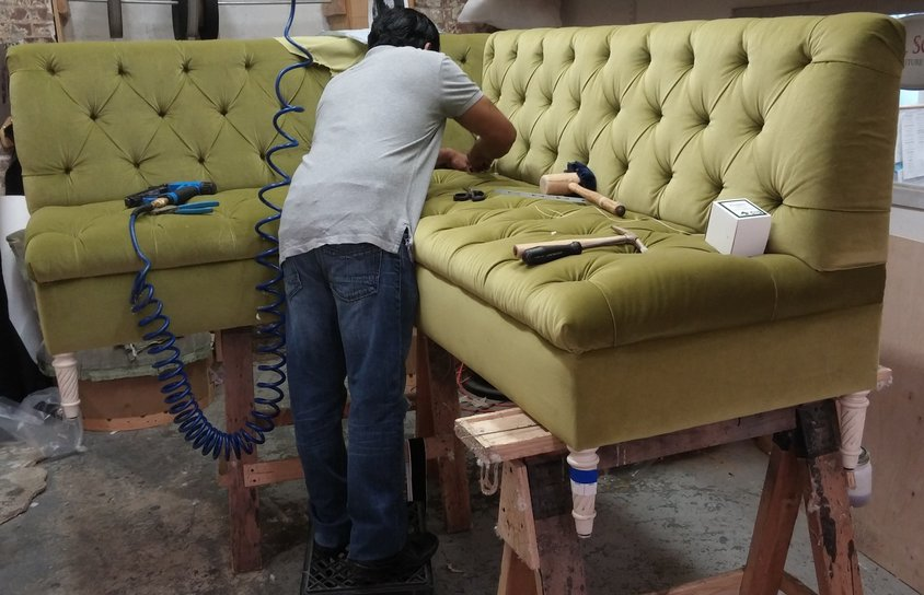 man fixing green tufted sofa