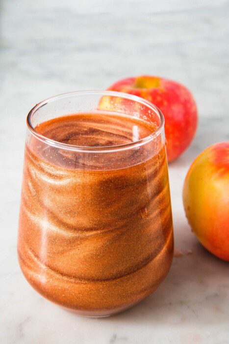 An apple cocktail with edible gold glitter swirling inside it