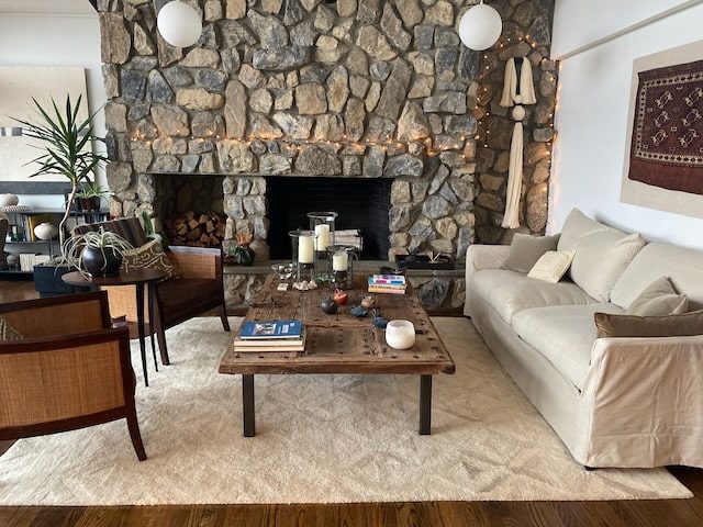 A beige sofa in a living room with a stone backsplash. 