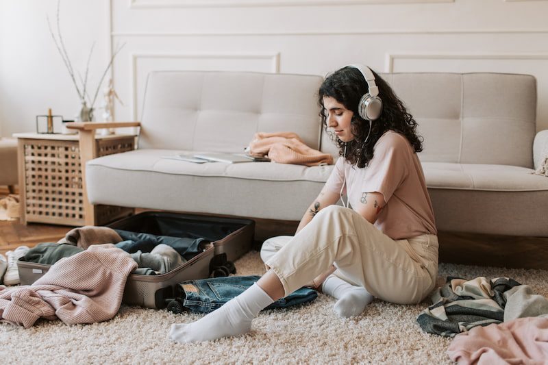 Girl sitting on floor folding clothes. 